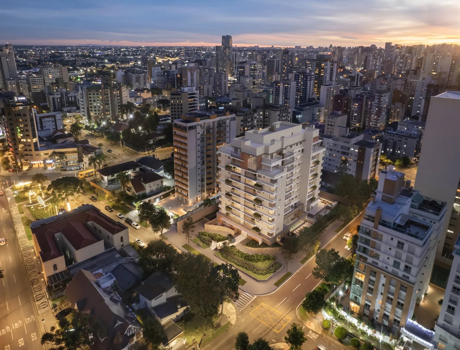 Vista aérea de Curitiba ao entardecer, com a torre da Casa Constant iluminada